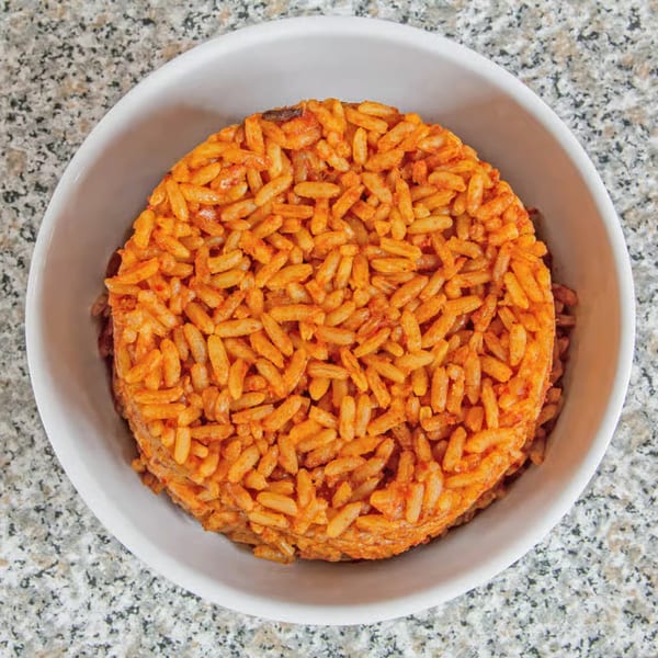 A white bowl filled with vibrant orange Jollof rice, a popular African dish from Suya Spot.
