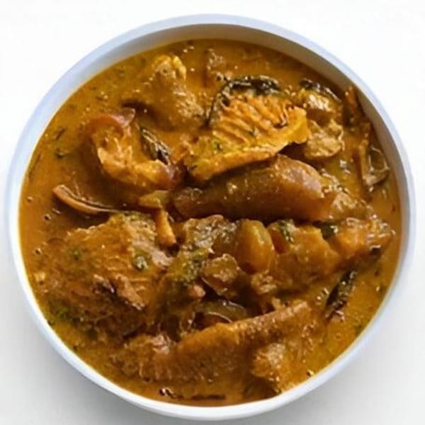 A bowl of rich, orange-brown African soup with various meats and vegetables.
