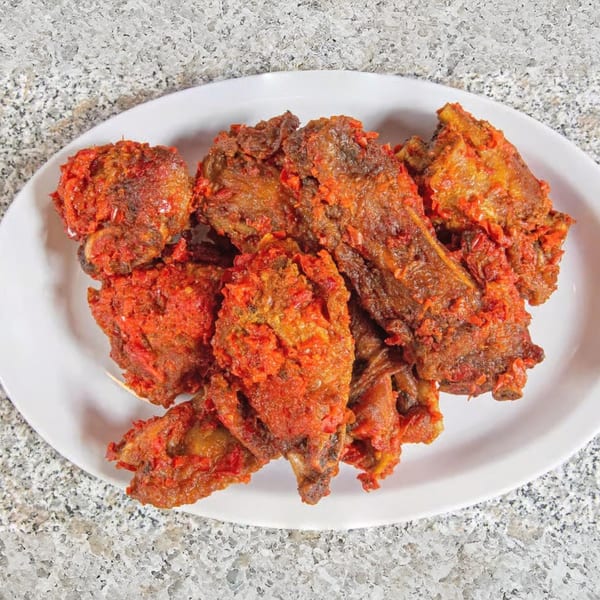 A white oval plate filled with Suya Spot's spicy African fried chicken pieces.
