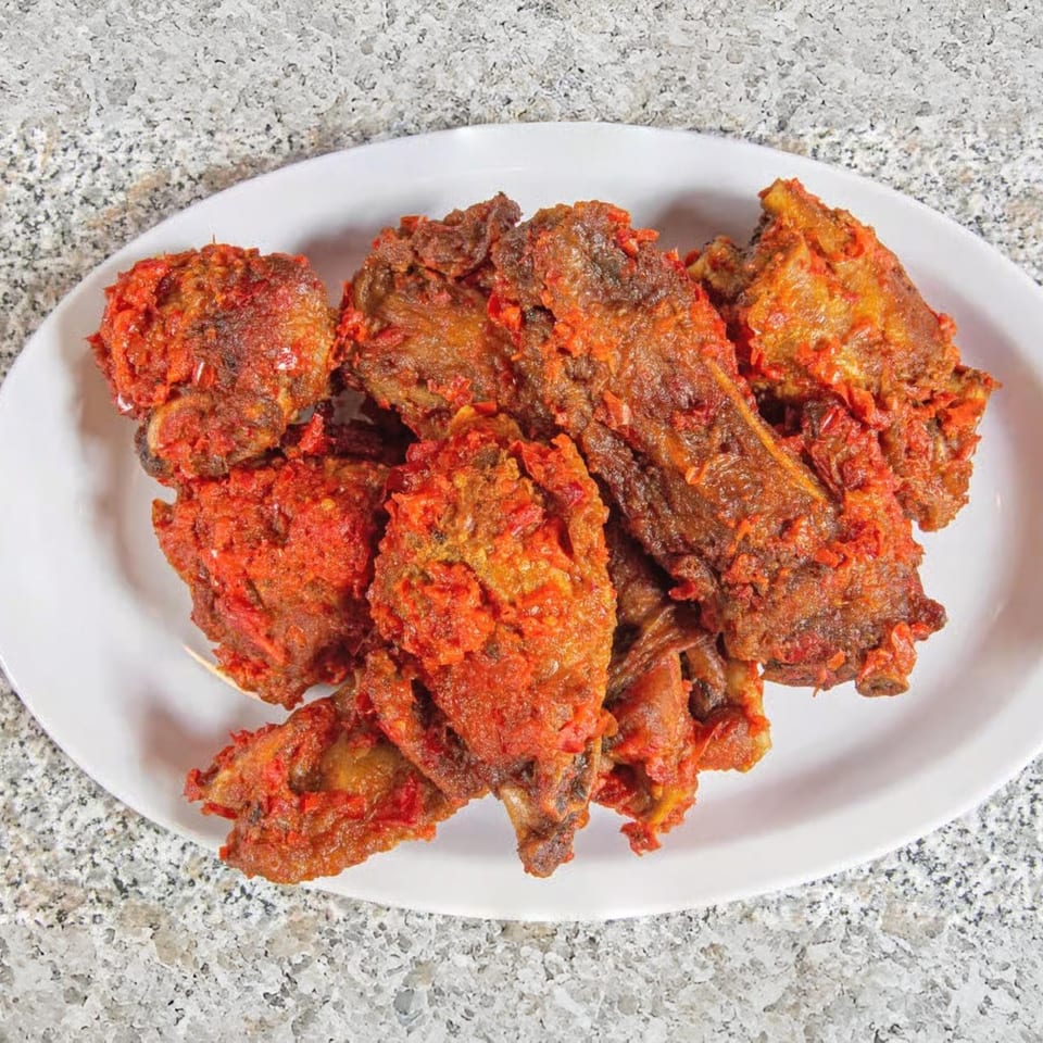 A white oval plate filled with Suya Spot's spicy African fried chicken pieces.