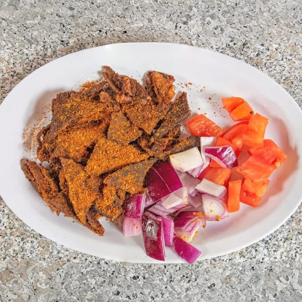 Suya Spot's African suya, a spicy grilled meat dish, served with diced red onions and tomatoes.